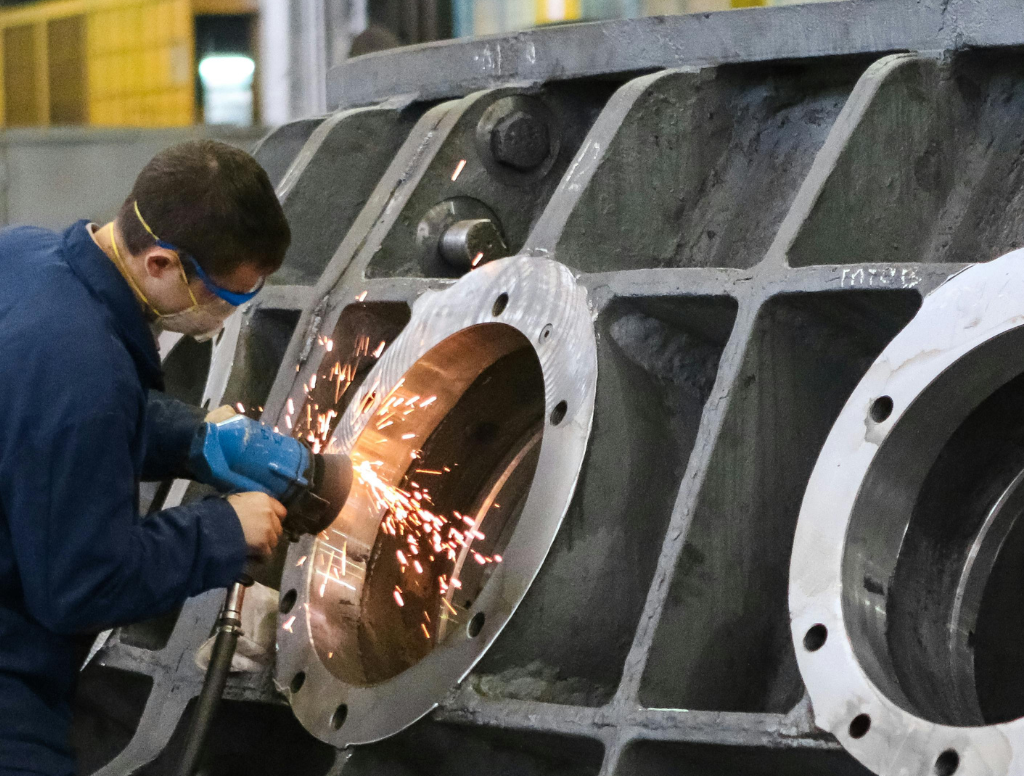 Monteur slijpt metaal in industriële werkplaats met veiligheidsbril en VCA-werkprocedures